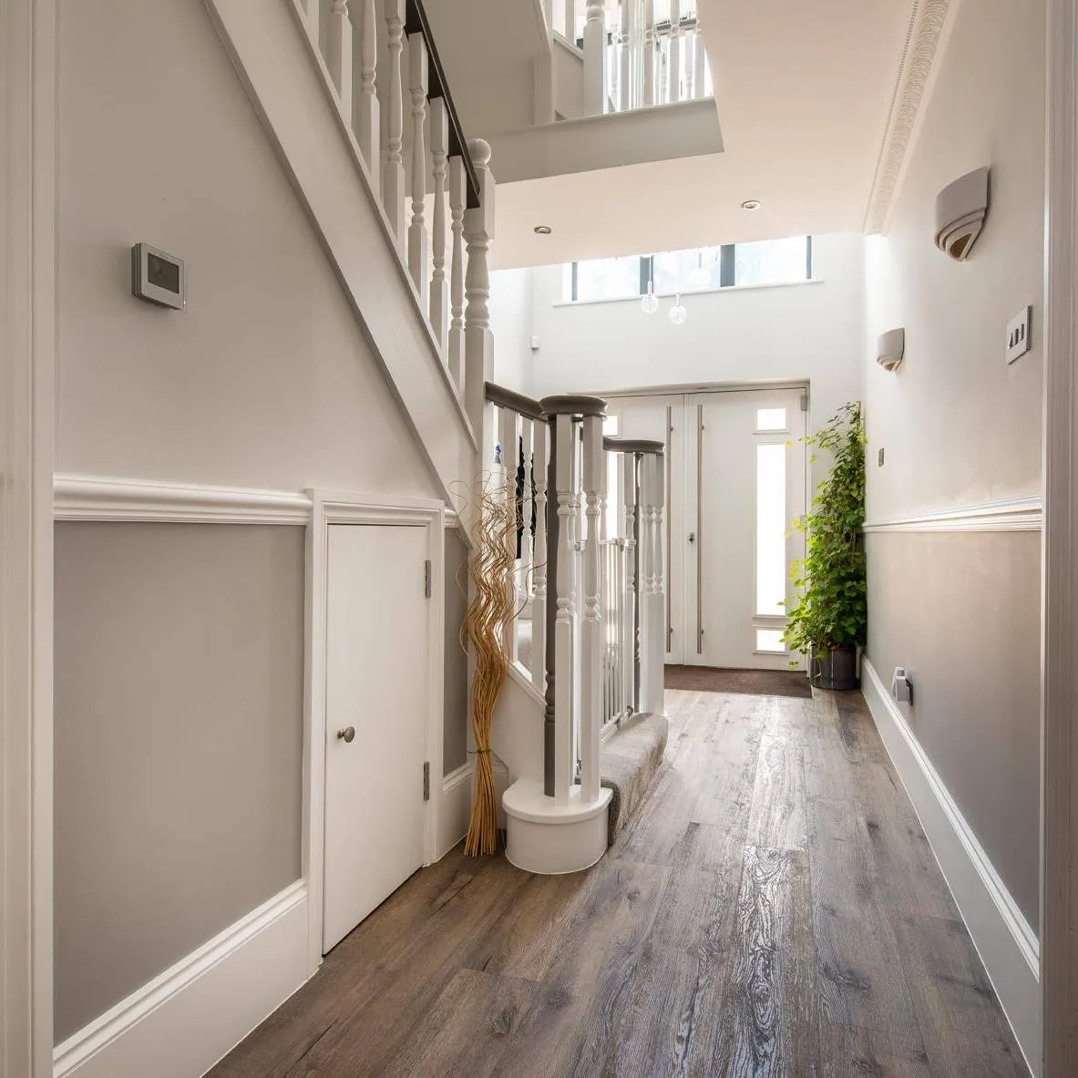 A hallway with a staircase and a glass door.