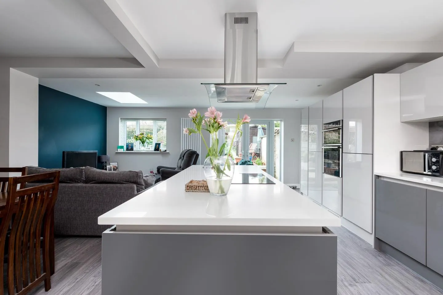 A kitchen with a centre island with a vase of flowers on it.