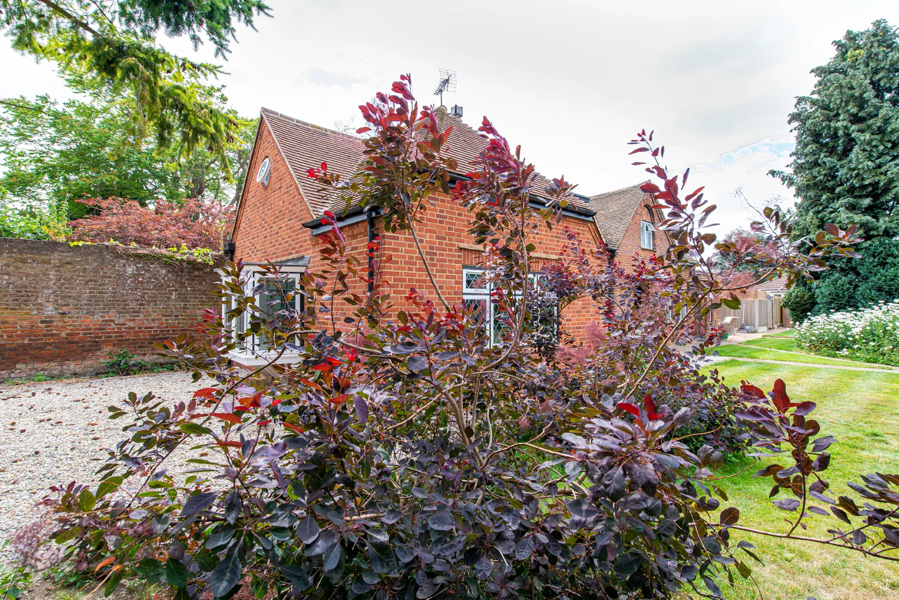 A red brick house with a bush in front of it.